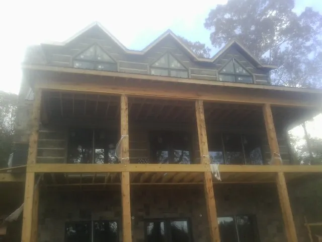 Dormers and porch framing on a large log home under construction — Roof Coating work by our crew in Lenoir
