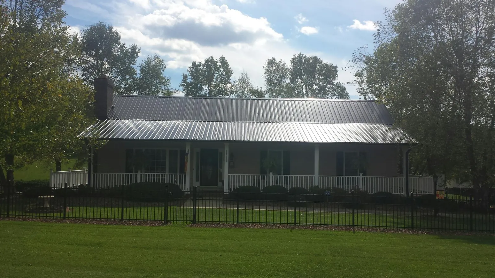 Gray metal roof on a brick ranch with a full width front porch — Gutter Guard Installation work by our crew in Lenoir